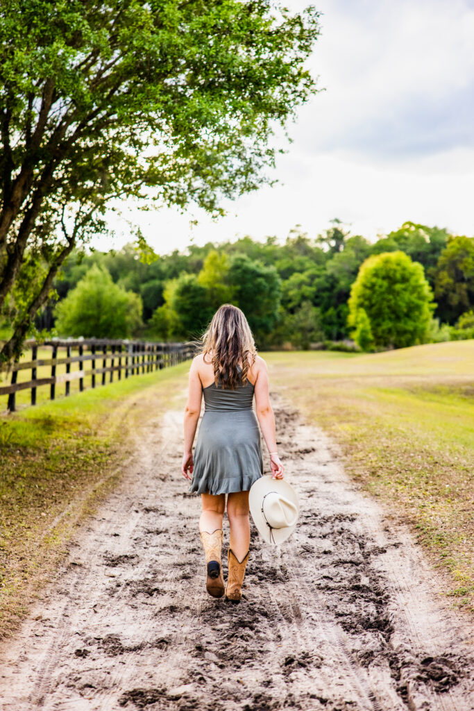 Image of a high school senior posing in a natural setting with a relaxed smile and a casual outfit, walking on a path. 